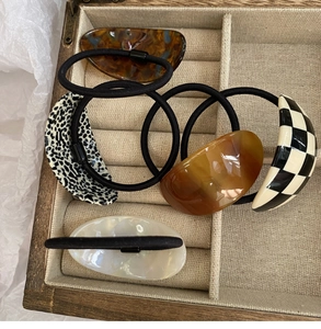 Detail view of five assorted acetate hair ties in shell and leopard patterns in a box