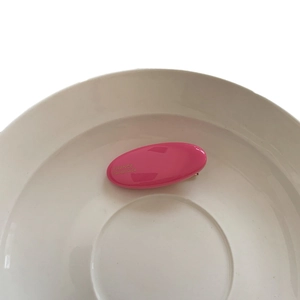 Pince à cheveux ovale rose en acétate avec texte doré France Handmade dans un bol