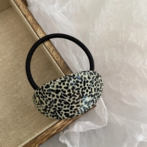 Close-up of acetic acid hair tie with black and white dalmation polka dot pattern