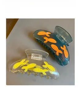 Detailed view of translucent acetate hair claws with sparkling crystal fish embellishments