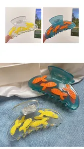 Detail shot of blue acetate hair claw with 3D cute fish design and crystal accents