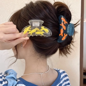 Blue acetate shark hair clips with 3D fish patterns shown on long brown hair