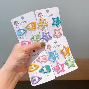 Close-up of colorful matte star and heart hair clips on white card holder packaging
