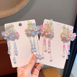Detailed close-up of handmade floral hair clips with translucent petals and bead tassels