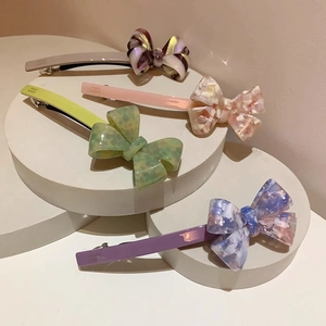 Detail showing four acetate bow hair clips in various patterns on a round display stand