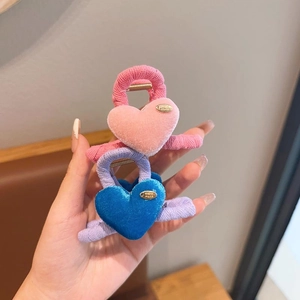 Detail of pink and blue velvet heart hair claws featuring a gold handmade metal tag