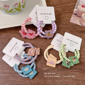 Colorful elastic hair ties with cute cartoon patches on white cards over wooden background