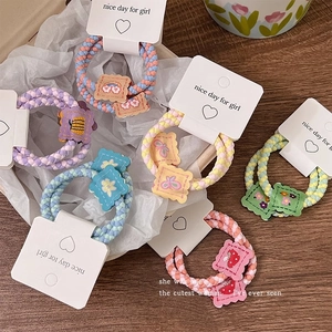 Close-up of elastic woven hair ties with cute cartoon patches on white cards