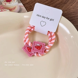 Detail of woven strawberry hair ties in a ceramic dish with soft pink embroidery and textures