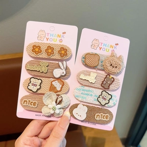 Detailed view of hand holding cute bear and bunny hair clip sets with soft fabric textures
