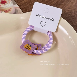 Detail of purple woven hair tie with cute cookie charms and elastic band on a cream tray