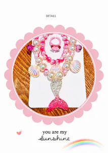Detail of girls' mermaid tail necklace set with pink beads, shell charm and heart ring
