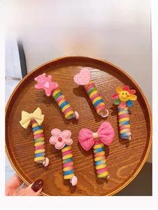 Close-up of six colorful spiral hair ties with cute cartoon charms on a wooden tray