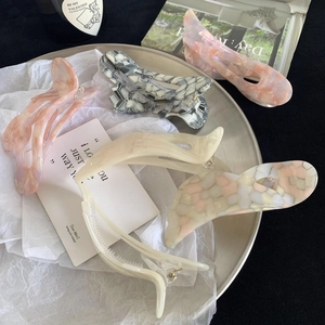 Close-up of premium acetate hair claws in various marble patterns on a silver tray