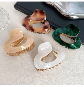 Detail of four colors of heart-shaped hollow acetate hair claws with gold metal base