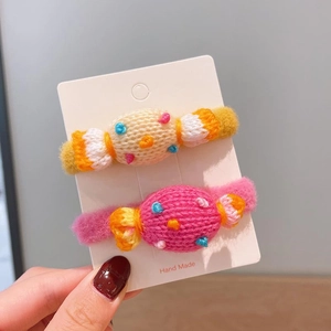 Dettaglio di due elastici per capelli fatti a mano a forma di caramella rosa e beige