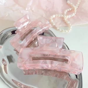 Detailed macro shot of pink marble texture acetate hair claw clip on silver tray