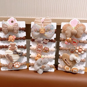 Close-up of elastic hair ties with plush bows, bear charms, and fabric flower details