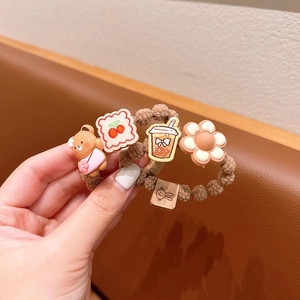 Detail of coffee-colored hair ties with cute cartoon bears, cherry toast, and white flowers