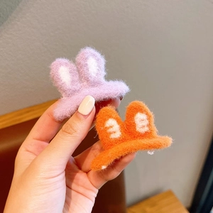 Close-up of plush rabbit ear hair clips in lavender and orange fuzzy knit texture