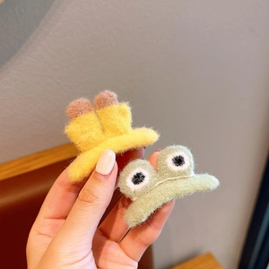 Close-up of soft plush frog and banana hair clips with detailed knit texture
