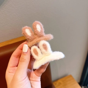 Detailed view of plush rabbit ear hair clips in pink and white soft knit fabric