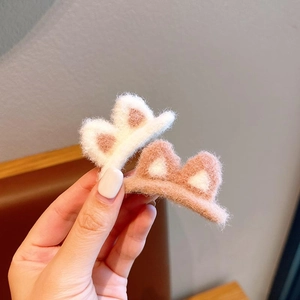 Close-up of soft plush cat ear hair clips in white and pink faux lamb wool texture