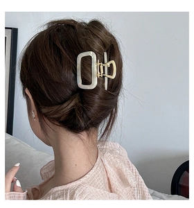 Detail of elegant cream acetate rectangular hair claw clip with gold metal spring