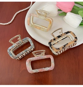 Detail of four acetate hollow square hair claws in assorted marble and floral patterns