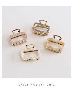 Close-up of four rectangular acetate hair claws with gold frames and marble textures