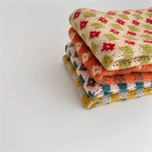Close-up of thick knitted winter scarves for kids with vintage floral and geometric patterns