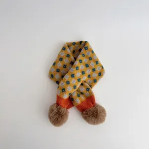 Detailed view of winter knit scarf with geometric patterns and brown faux fur pom-poms
