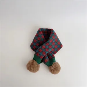 Detail of winter knit scarf with checkered pattern and soft brown faux fur pom-poms