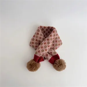 Detailed view of pink knitted scarf featuring argyle pattern and brown pom-pom accents