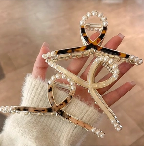 Detail of tortoise shell acetate claw clip with pearl trim and cross ribbon design