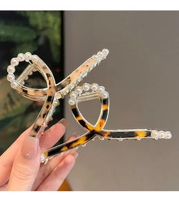 Detailed macro view of large tortoise shell hair claws with elegant pearl embellishments