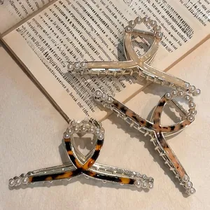 Close-up of elegant large pearl hair claws with leopard pattern and marble finish texture