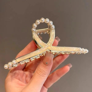Close-up of gold shark clip featuring mother-of-pearl finish and white pearl edge detail