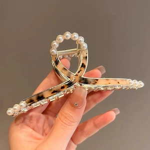 Detail of tortoise shell hair claw clip with gold metal frame and white pearl accents