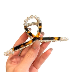 Elegant tortoiseshell claw clip with pearls and gold metal cross frame for hair styling