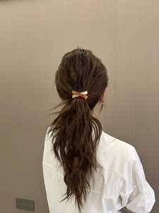 Detail view of the elegant resin and gold metal cross hair clip on a ponytail