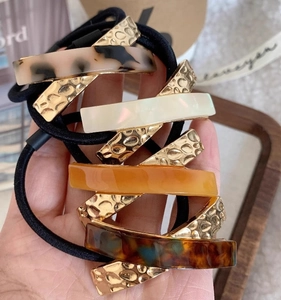 Close-up of four durable elastic hair ties with gold-tone metal and acetate details