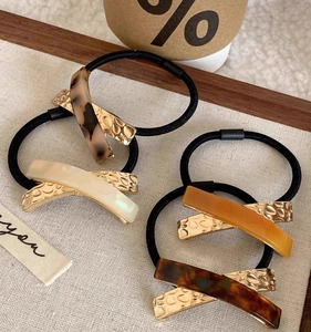 Detailed close-up of acetate and metal stitching hair ties in four vintage colors