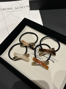 Detailed macro view of four premium elastic hair ties with gold metal and acetate X-shaped bars