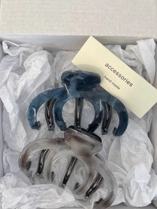 Detail of blue and taupe marble texture acetate hair claws in a white gift box