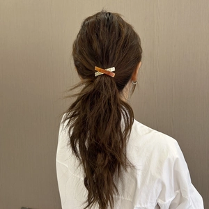 Elegant tortoiseshell acetate and gold metal X-shape hair tie for high ponytail styles
