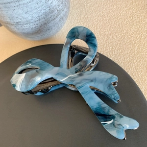 Detailed macro view of bow-shaped blue marble acetate hair claw clip with metal spring