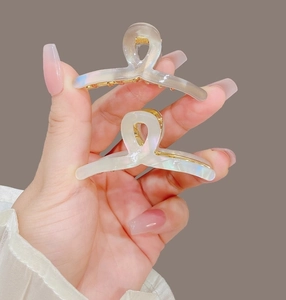 Détail de deux mini pinces à cheveux nacrées avec un design croisé minimaliste