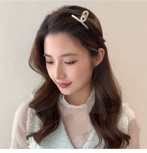 Pince à cheveux élégante blanc nacré avec base dorée montrée sur modèle pour coiffure