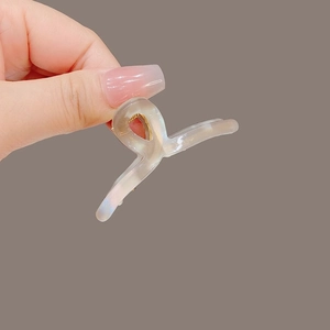 Détail d'une petite pince à cheveux irisante avec ressort doré pour coiffures demi-attachées